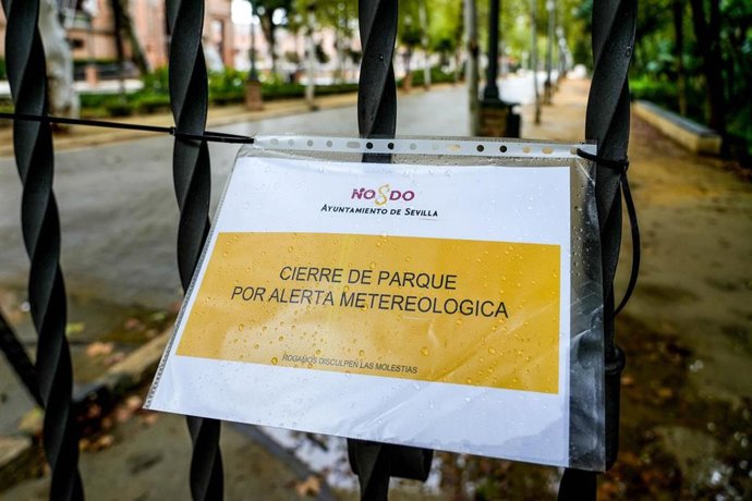 Archivo - Cartel en una reja de entrada al Parque de María Luisa que indica el cierre por alerta meteorológica,en foto de archivo.