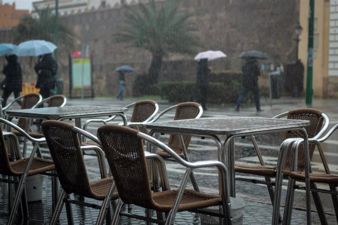 Veladores vacíos a causa de la lluvia en el entorno de la Catedral de Sevilla.