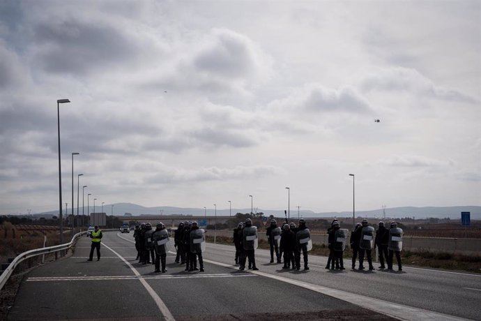 Varios antidisturbios acuden a una carretera cortada por decenas de agricultores durante la tercera jornada de protestas de los ganaderos y agricultores para pedir mejoras en el sector, en la autovía A-3, a 8 de febrero de 2024, en Valencia