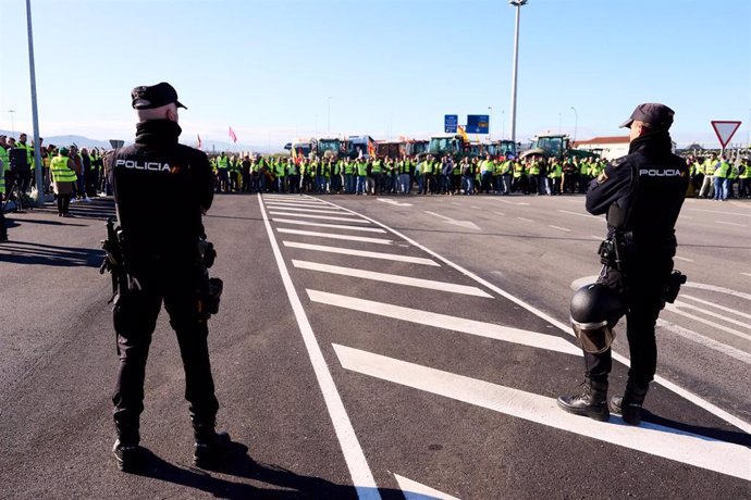 Dos agentes de la Policía Nacional delante de la manifestación de agricultores y tractores en el puerto de Santander