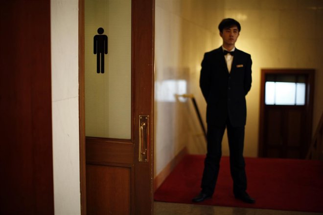 A security officer stands next to the door of a bathroom at The Great Hall of th
